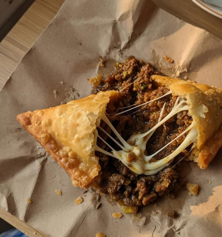 Mutton cheese samosa opened to dark minced mutton and melted cheese.